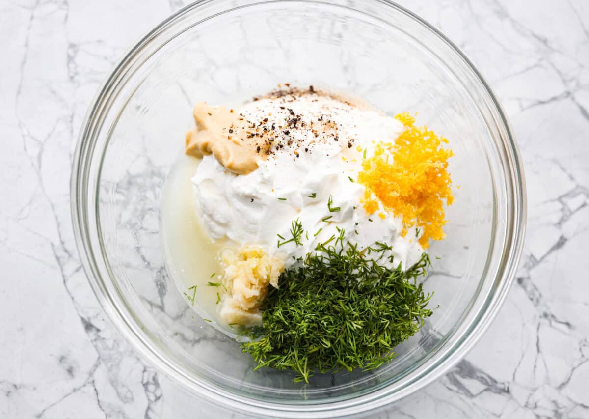 This creamy lemon dill sauce is fresh, tangy, and packed with flavor! Itโs the perfect complement to salmon, roasted veggies, or even as a dip for crispy potatoes. Made with simple ingredients like fresh dill, lemon, and a touch of garlic, it comes together in minutes! Overhead shot of all of the ingredients in a mixing bowl.