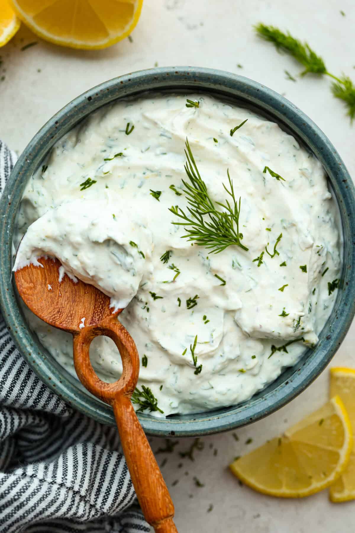 This creamy lemon dill sauce is fresh, tangy, and packed with flavor! Itโs the perfect complement to salmon, roasted veggies, or even as a dip for crispy potatoes. Made with simple ingredients like fresh dill, lemon, and a touch of garlic, it comes together in minutes! Overhead image of lemon dill sauce in a small serving bowl with wooden spoon.