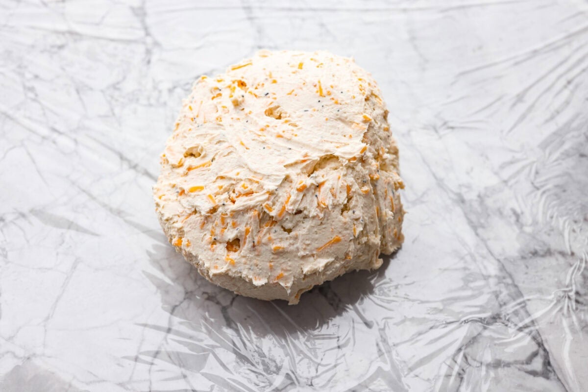 This everything bagel cheese ball combines the creamy richness of cheese with the savory blend of everything bagel seasoning! It's an irresistible appetizer you can serve with crackers, bagel chips, or veggies! Everyone will love it! Overhead shot of the cheeseball formed into a ball.