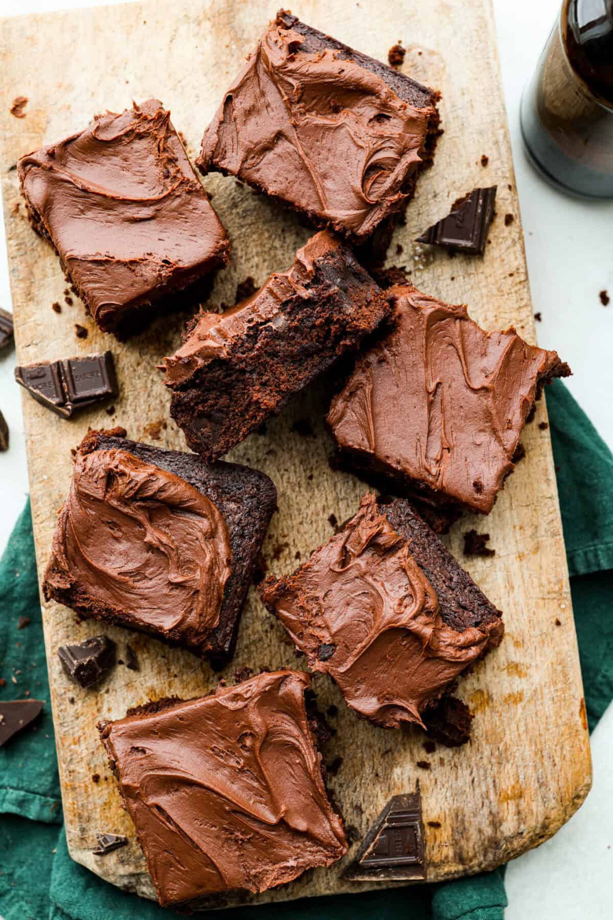 Rich, fudgy, and packed with deep chocolate flavor, Guinness Brownies are a must-try for any dessert lover! The stout beer enhances the cocoa, adding a subtle, malty depth of flavor that makes these brownies rich and irresistibly delicious. Overhead shot of servings of Guinness brownies on a wooden serving board.