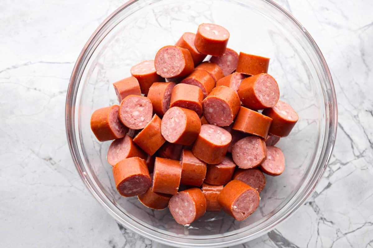 Kielbasa Bites are the ultimate crowd-pleasing appetizer! With their smoky, savory flavor and caramelized glaze sweetness, these bite-sized snacks are easy to make and always a hit at parties, game days, or anytime you need a quick appetizer! Overhead shot of sliced kielbasa in a bowl.