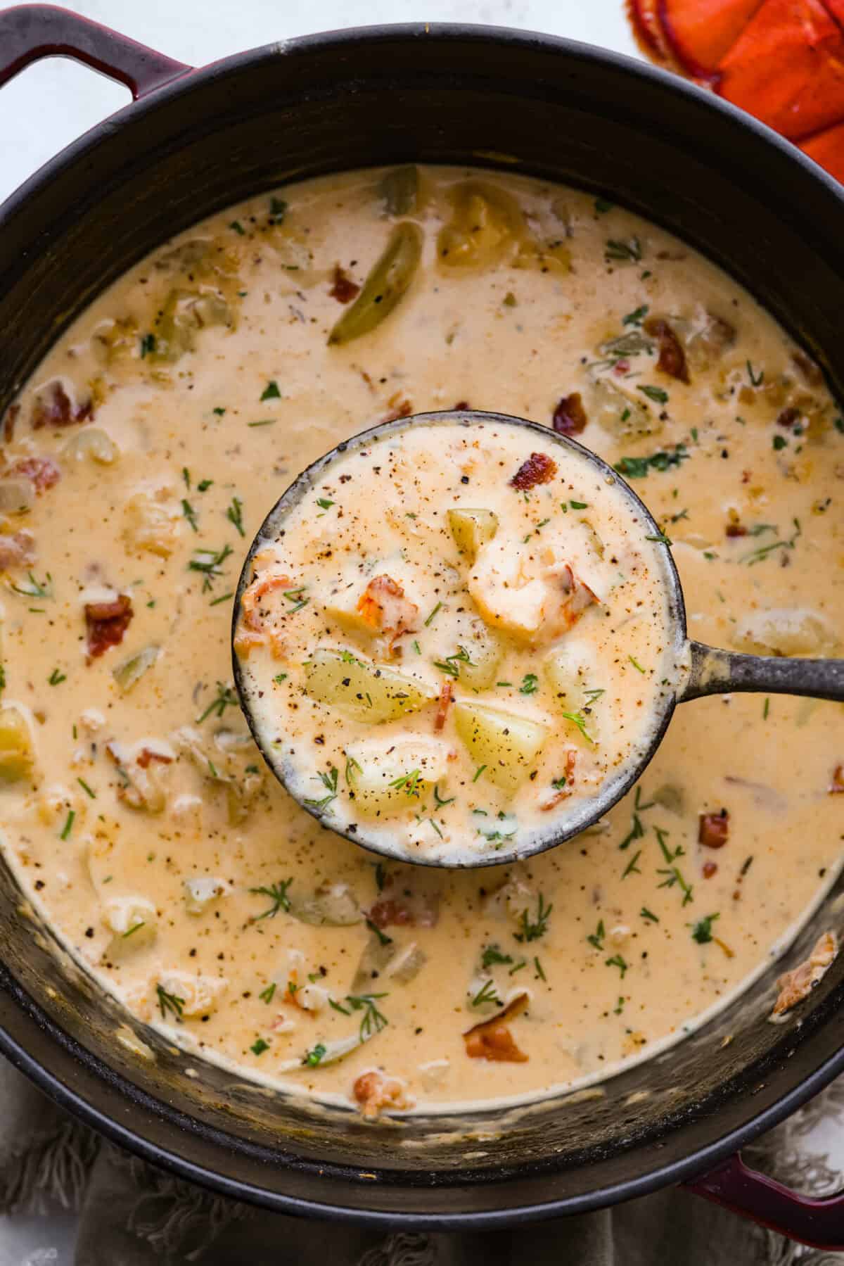 Creamy, indulgent Lobster Chowder takes only 40 minutes to make and is incredibly flavorful! Tender potatoes, crisp bacon, and luscious lobster are enveloped in a creamy, velvety broth. It would be a great soup to serve on Valentine's Day or a special occasion, but easy enough for any night of the week. Overhead shot of lobster chowder in a pot with a ladle.