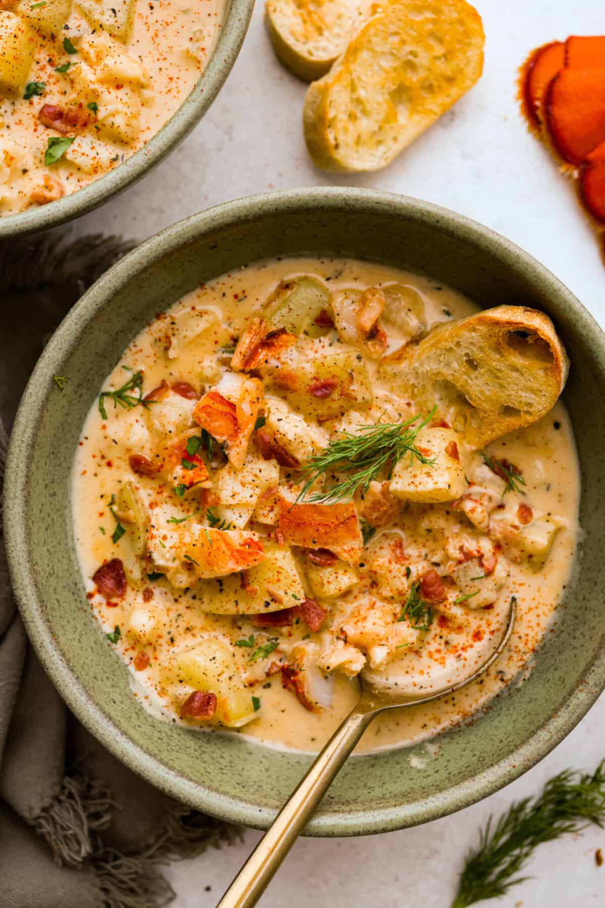 Creamy, indulgent Lobster Chowder takes only 40 minutes to make and is incredibly flavorful! Tender potatoes, crisp bacon, and luscious lobster are enveloped in a creamy, velvety broth. It would be a great soup to serve on Valentine's Day or a special occasion, but easy enough for any night of the week. Overhead shot of a bowl of lobster chowder.