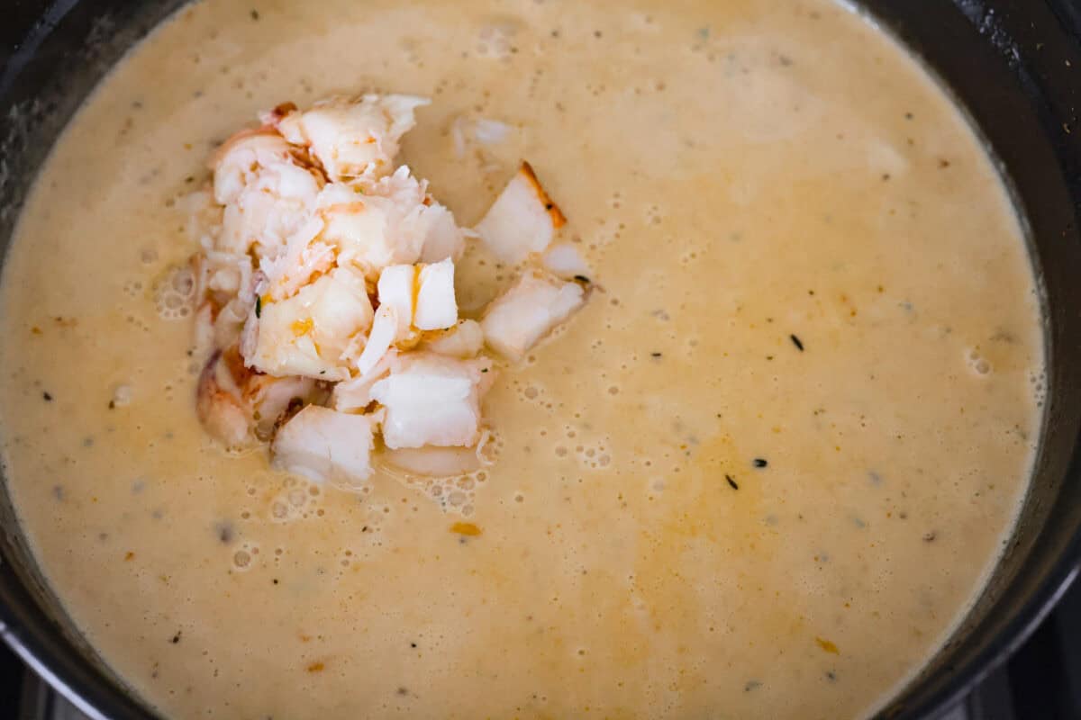 Creamy, indulgent Lobster Chowder takes only 40 minutes to make and is incredibly flavorful! Tender potatoes, crisp bacon, and luscious lobster are enveloped in a creamy, velvety broth. It would be a great soup to serve on Valentine's Day or a special occasion, but easy enough for any night of the week. Overhead shot of the lobster on top of the soup.