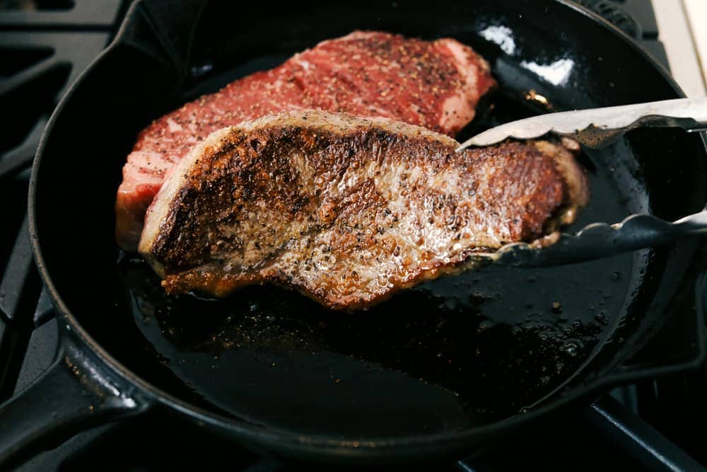 Steak Frites is a classic French bistro dish that combines perfectly seared, juicy steak with crispy, golden fries. It's a simple yet delicious meal that is filled with rich flavors and satisfying crunch. You will love this restaurant-quality dinner made right in your own kitchen! Angle shot of seared steak.