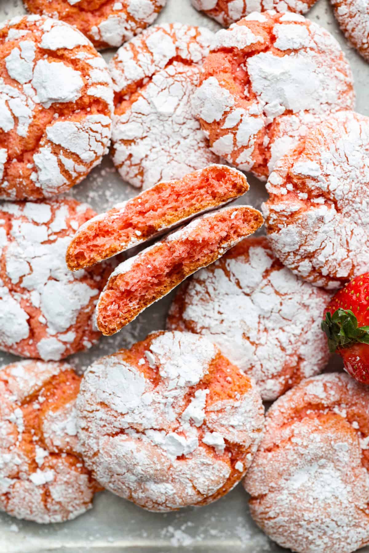 Strawberry Crinkle Cookies are the perfect blend of soft and chewy with a sweet, powdered sugar coating. Their vibrant color and classic strawberry cake flavor make them perfect for any occasion. Close up shot of strawberry crinkle cookies.