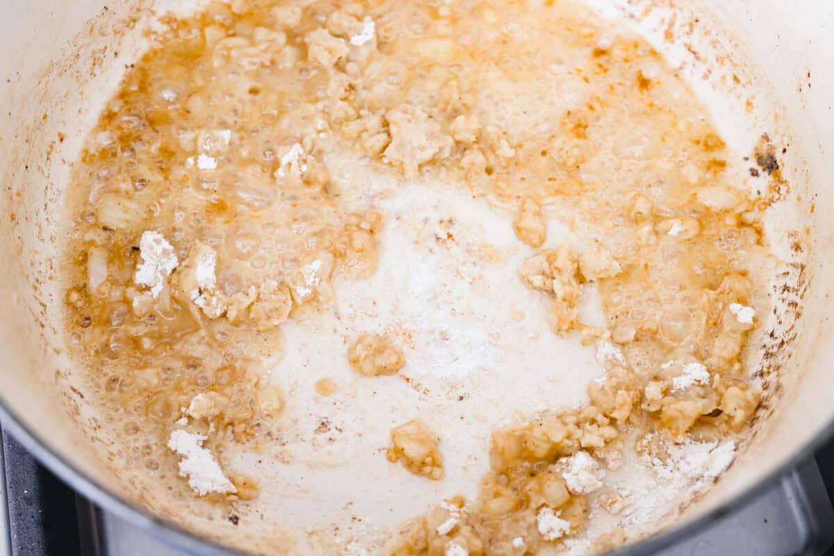 Warm and comforting, this cozy Swedish meatball soup is the perfect meal for chilly days. Juicy meatballs simmer in a rich, savory broth with tender noodles, making every spoonful satisfying. It’s easy to make and sure to become a family favorite! Overhead shot of onions cooking in a pot with butter, garlic, and flour. Creating a roux for the base of Swedish meatball soup.