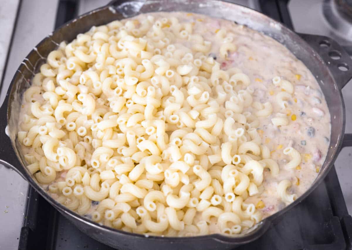 Creamy, cheesy Cowboy Mac and Cheese gets a bold twist with hearty additions like seasoned meat, tomatoes, jalapeรฑos, corn, beans, and onions. It's rich, flavorful, and just the right amount of spice! The heat is warm but not overwhelming. If you like it spicy, add more jalapeรฑos! Cooked noodles are added to the skillet with the cheesy, creamy beef mixture.