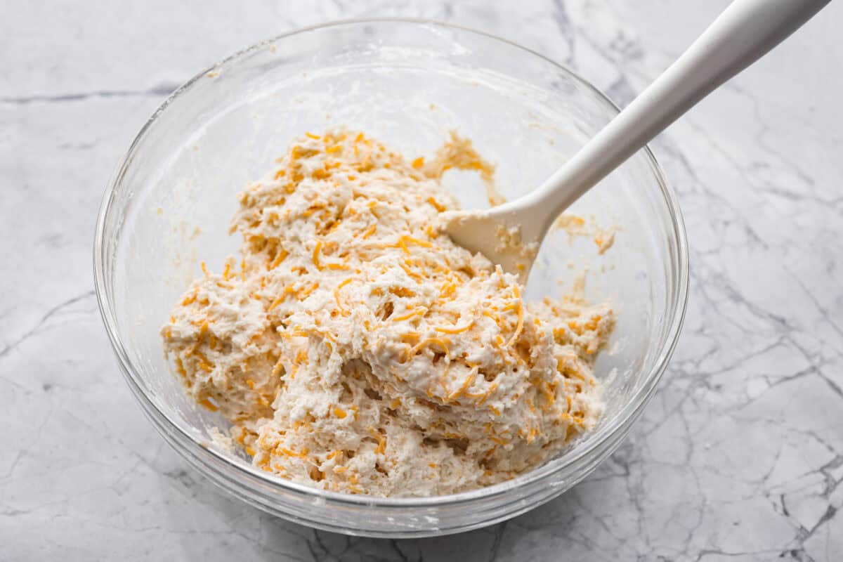 These cheesy beer bread muffins are light, fluffy, and packed with savory flavor! The key is to not overmix the batter. Mixing until just combined will give you the perfect airy, melt-in-your-mouth texture that will keep you coming back for more. A mixing bowl with the wet and dry ingredients combined.