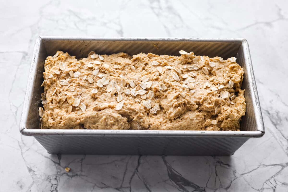 Irish Brown Bread is a delicious twist on classic soda bread, offering a slightly sweet, rich, and hearty flavor. It comes together quickly and makes a great breakfast, snack, or side with dinner. It's so yummy with honey, butter, or jam! Overhead shot of the bread dough in a loaf pan ready to go into the oven.
