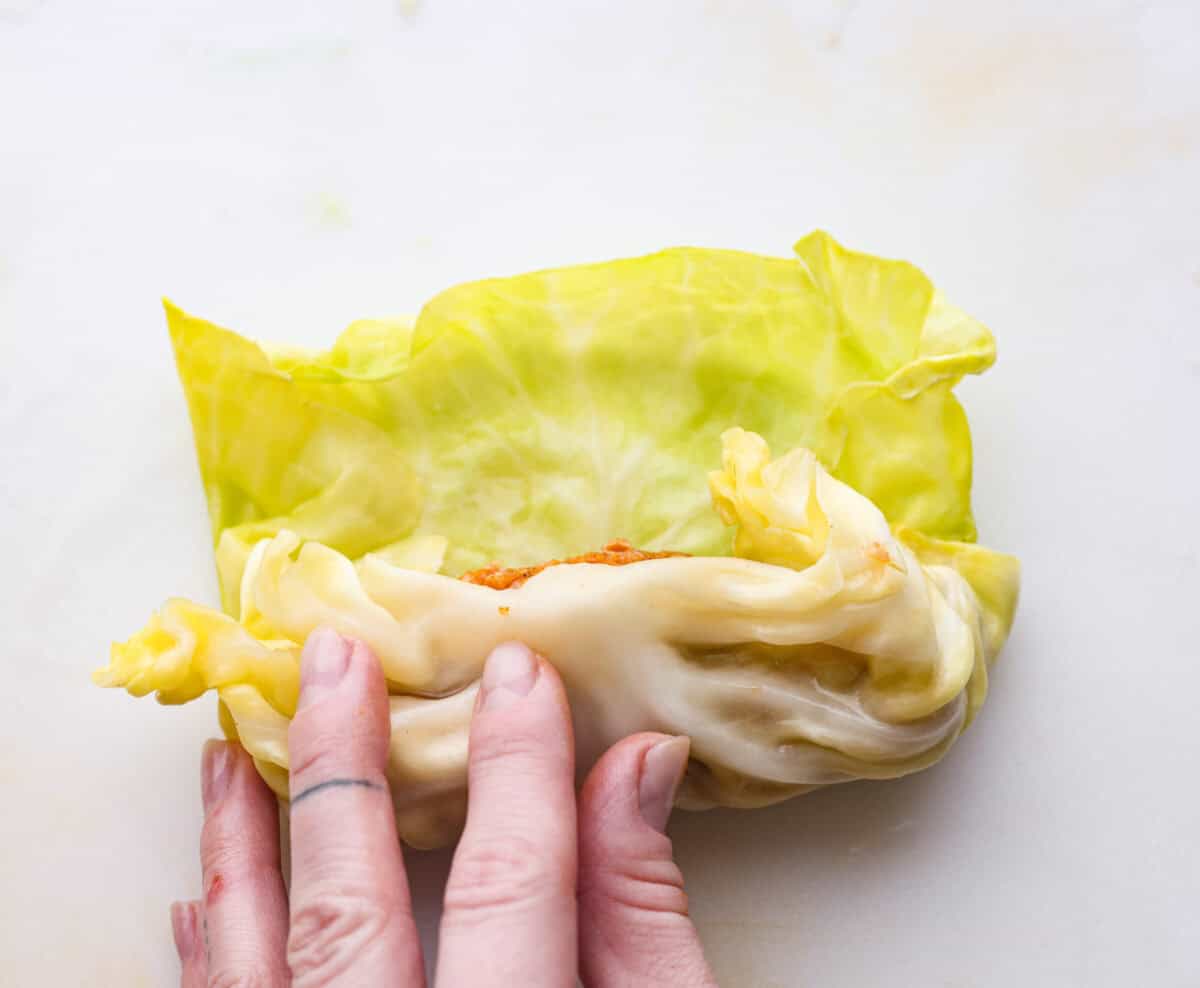Hungarian cabbage rolls are packed with rich, hearty flavors in every bite! I know you love a good cabbage roll and can’t get enough of my Hungarian goulash, so I knew this recipe would be perfect. Close up shot of someone rolling up the filling in the cabbage leaf.