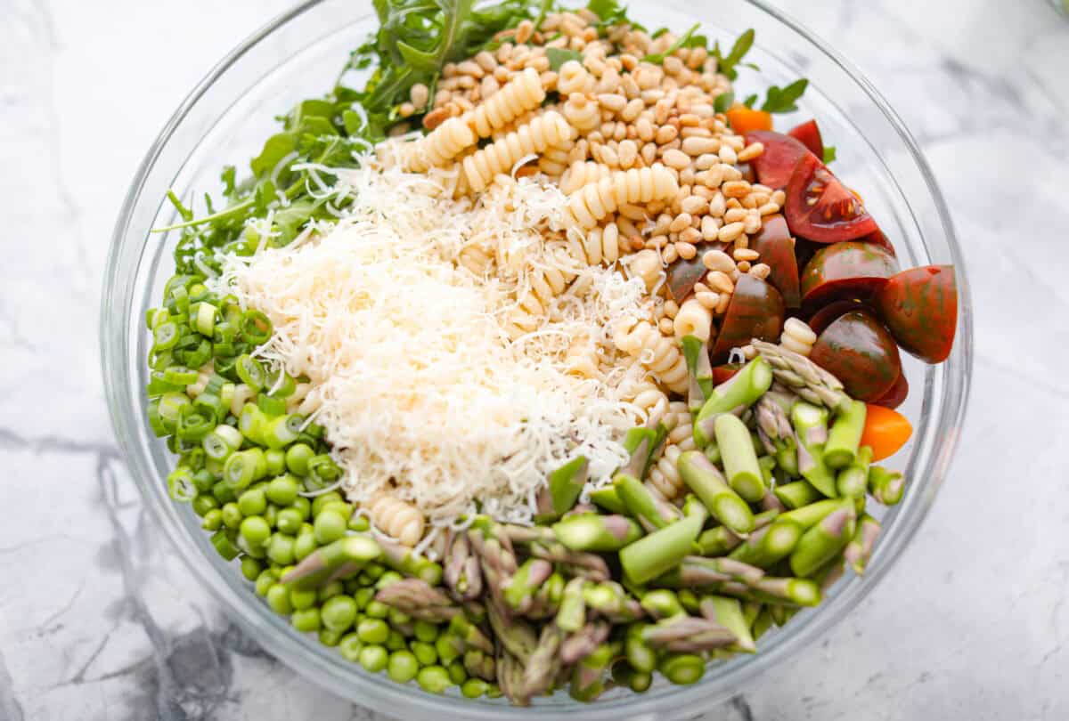 This Green Goddess Pasta Salad is fresh, vibrant, and full of flavor! The creamy herb dressing adds a tangy twist, while crisp spring veggies make it light yet hearty. Perfect for potlucks or any time youโre craving a delicious side! Process shot of all of the pasta salad ingredients in a large bowl.