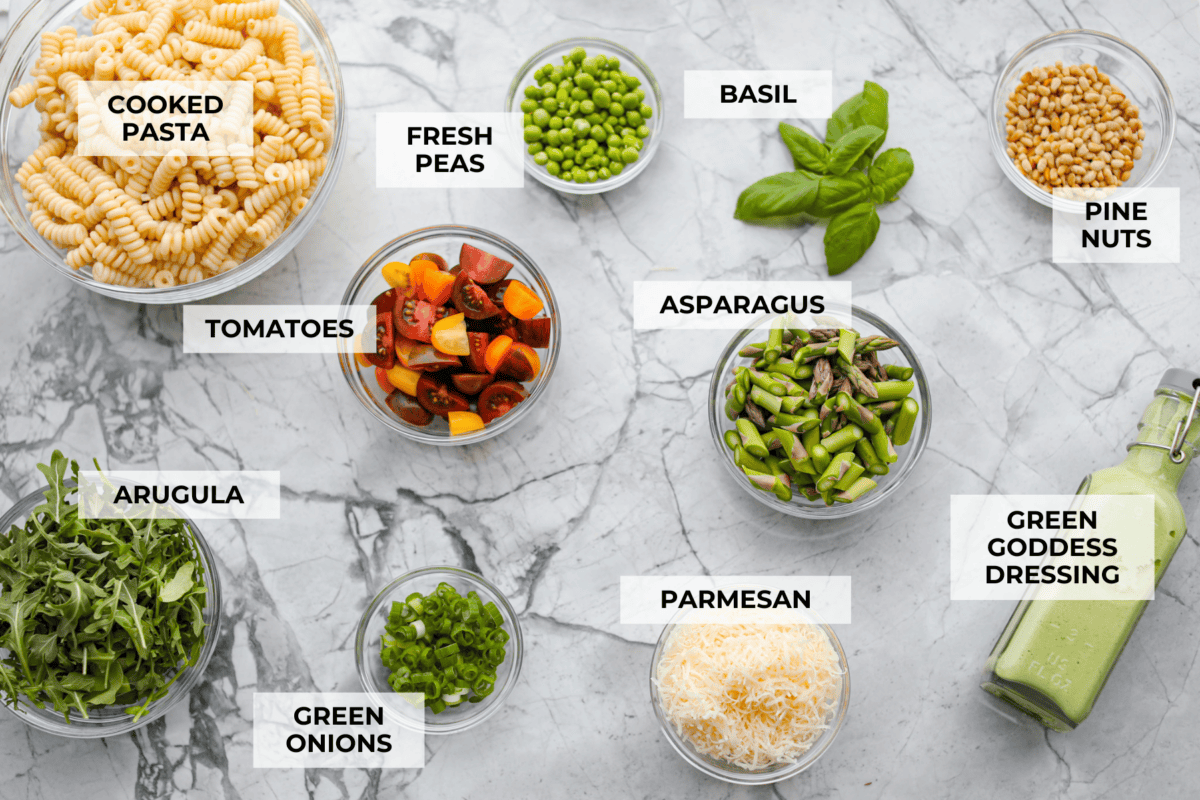 This Green Goddess Pasta Salad is fresh, vibrant, and full of flavor! The creamy herb dressing adds a tangy twist, while crisp spring veggies make it light yet hearty. Perfect for potlucks or any time youโre craving a delicious side! Overhead shot of labeled ingredients.