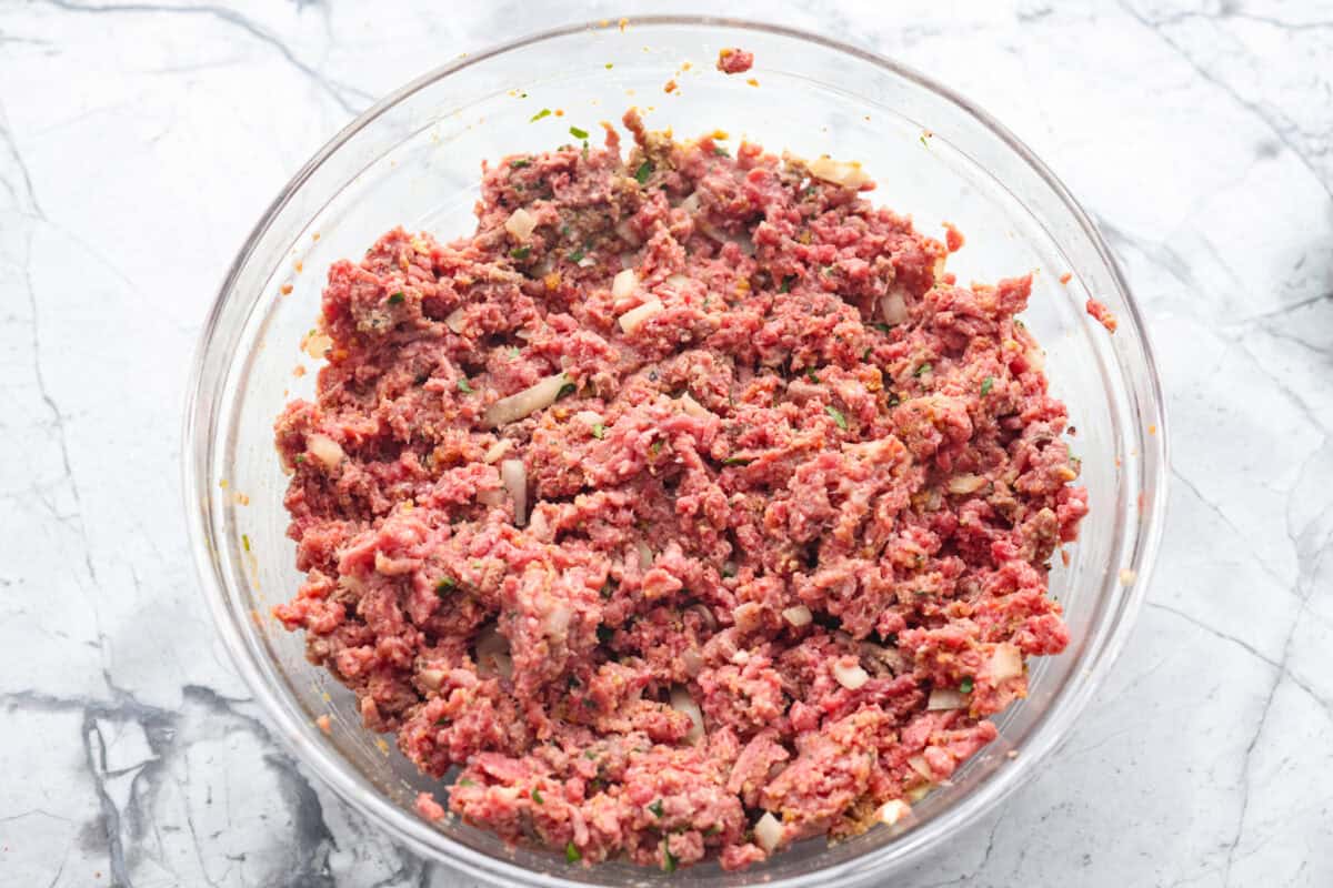 Turn classic meatloaf into amazing one-pan Meatloaf Casserole! Juicy, flavorful meatloaf and creamy mashed potatoes come together in one easy, delicious dish. Meatloaf ingredient combined in a bowl.