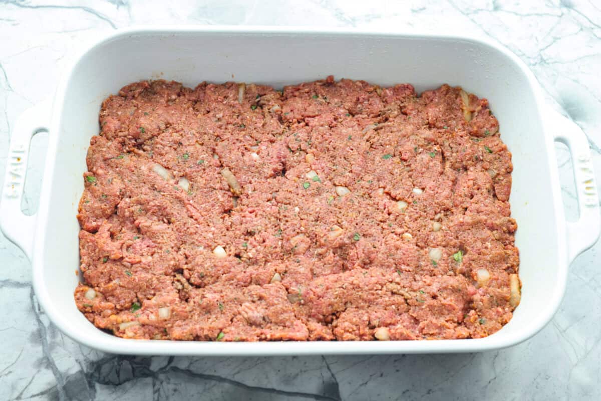 Turn classic meatloaf into amazing one-pan Meatloaf Casserole! Juicy, flavorful meatloaf and creamy mashed potatoes come together in one easy, delicious dish. Meatloaf ingredients pressed into the bottom of the baking dish.