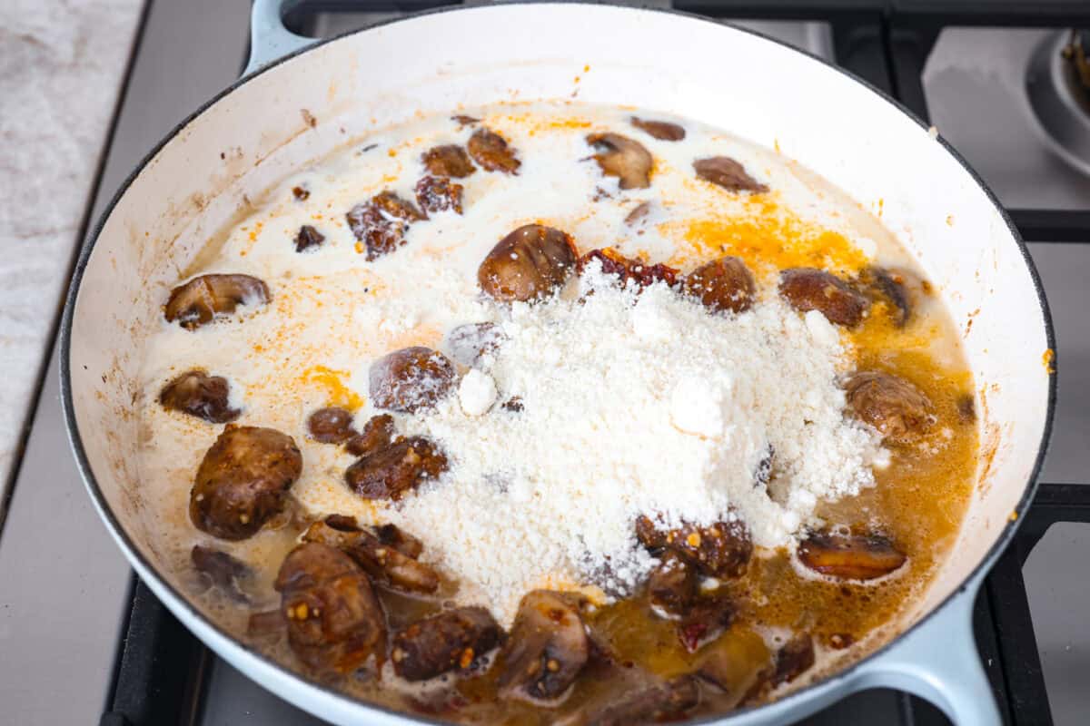 The key to making these Marry Me Mushrooms irresistibly flavorful is getting the perfect sear on the mushrooms. This locks in their natural flavors and texture. Then they simmer in a creamy garlic parmesan sauce with robust sun-dried tomatoes and herbs. It’s a simple technique that makes all the difference! Overhead shot of the cream and parmesan cheese added to the skillet.