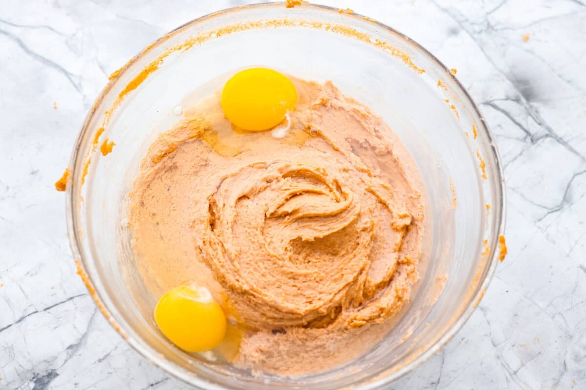 It's time to bring back the retro Tomato Soup Cake! In 1960, it was the first recipe to appear on a soup label. It resembles a moist and delicious spice cake topped with cream cheese frosting. I know you're skeptical, but trust me, it will knock your socks off! Wet and dry ingredients are all mixed together in a bowl with 2 eggs crack on top.