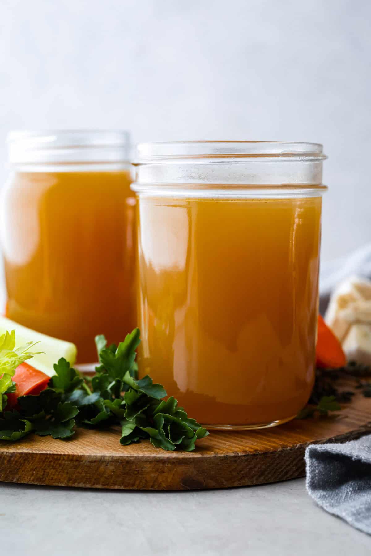 Homemade vegetable broth is light, delicate, and infused with the flavor of fresh vegetables. It's incredibly easy to make and great for using leftover veggies. The key is to not overcook the veggies. This can lead to a bitter flavored broth. Side shot of two mason jars filled with homemade vegetable broth.