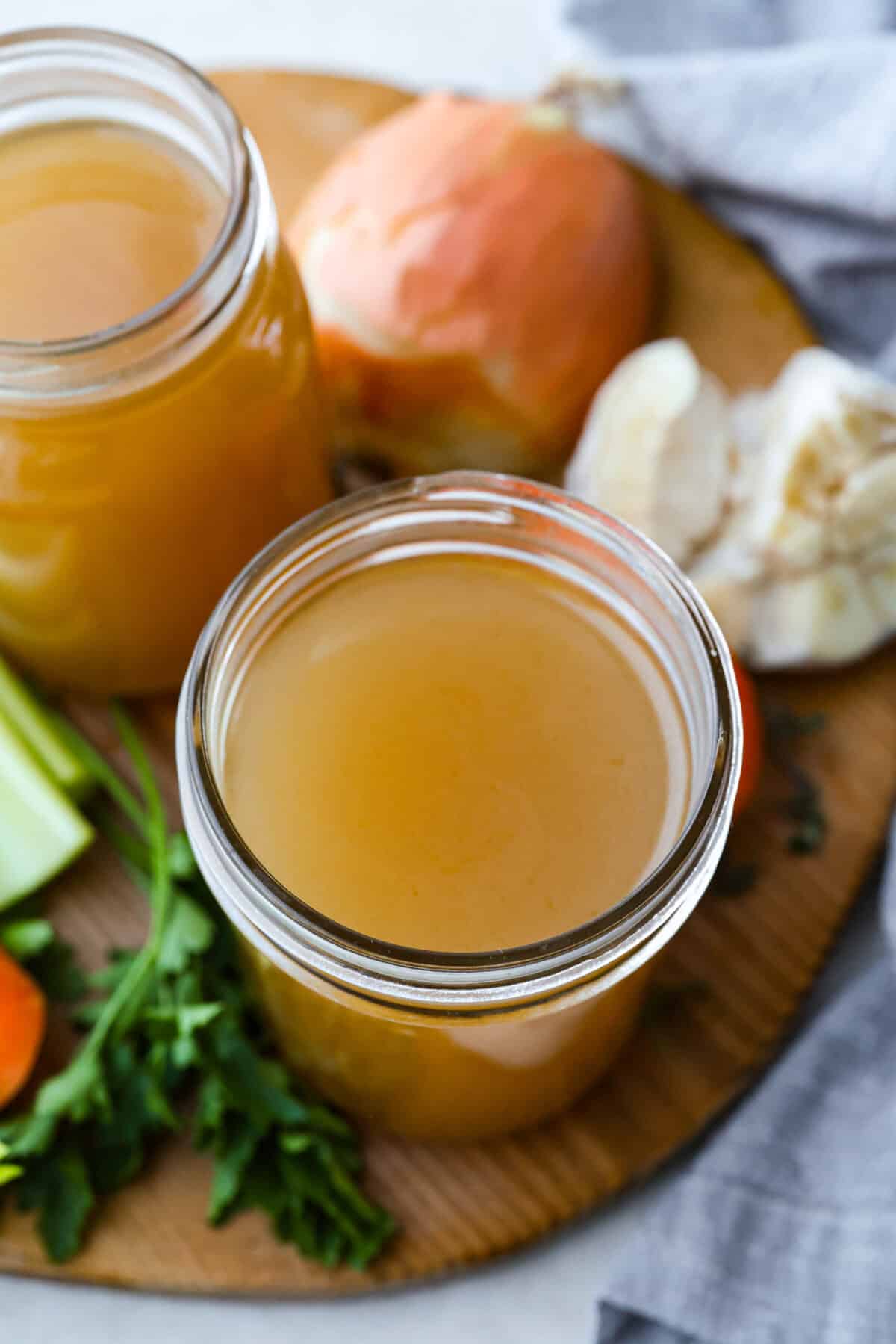 Homemade vegetable broth is light, delicate, and infused with the flavor of fresh vegetables. It's incredibly easy to make and great for using leftover veggies. The key is to not overcook the veggies. This can lead to a bitter flavored broth. Top down view of the mason jars filled with homemade vegetable broth.