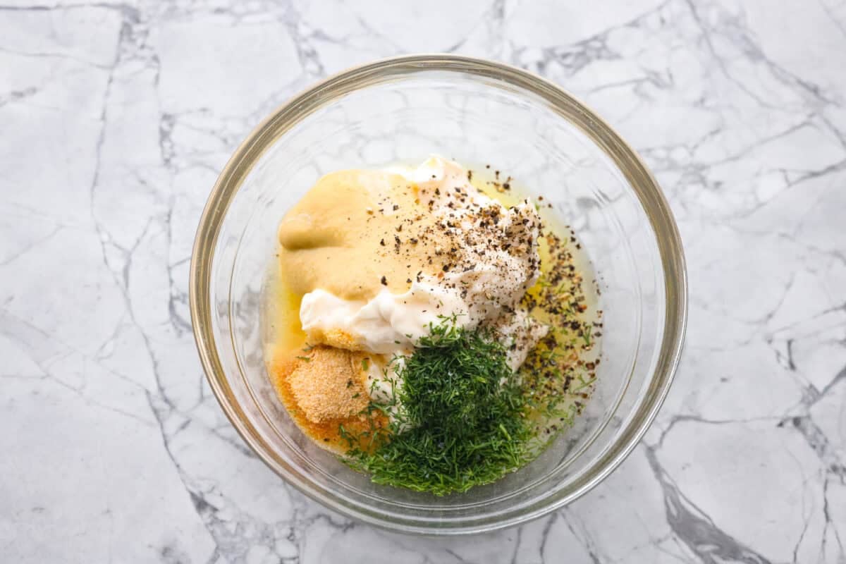 If you love that good pickle crunch, this high-protein Dill Pickle Chicken Salad is a must! It’s bold, zesty, and perfect for sandwiches or a snack right out of the bowl! Dill pickle dressing ingredients in a bowl.