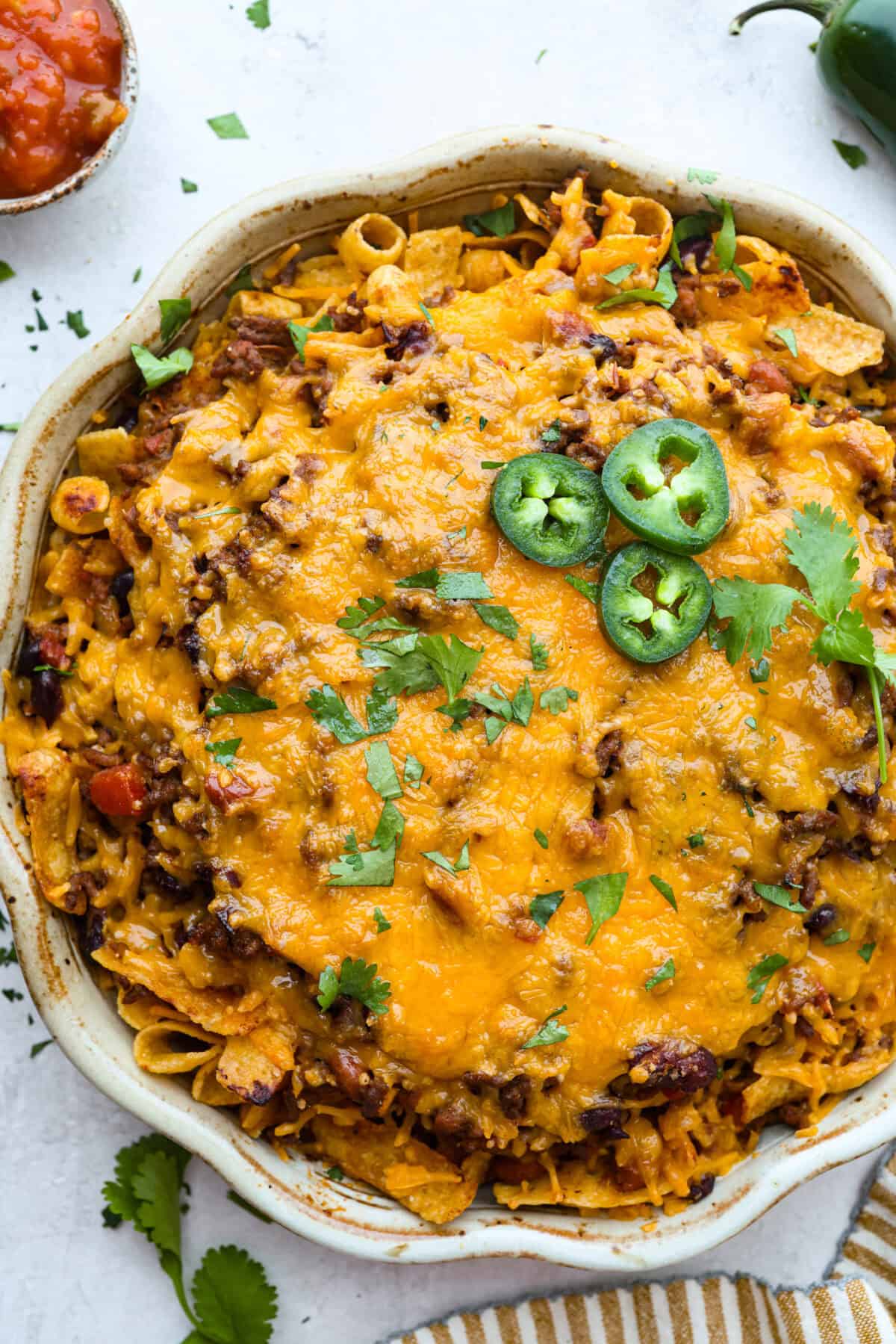 Not to be dramatic, but Frito Chili Pie might have saved my sanity. Zero whining, zero leftovers, it was a total dinner miracle. Crunchy, flavorful and ridiculously easy... you need this in your life ASAP. Overhead shot of Frito chili pie garnished with cilantro and jalapeรฑos.