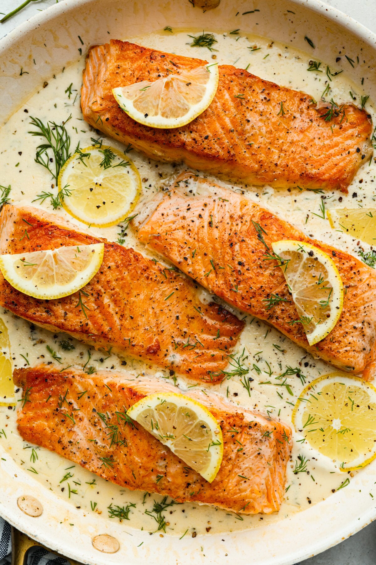 My Pan Seared Salmon has a new and improved Sauce! I added salt to bring out the flavors, and now it’s perfect! Fresh lemon juice and dill make it a match made in salmon heaven! Close up of the pan seared salmon in the pan.