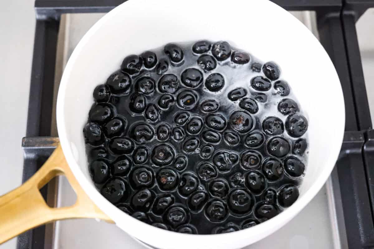 My homemade Blueberry syrup is next-level amazing! My secret ingredient? A splash of lemon! It’s the perfect balance to those sweet, juicy berries and makes your morning pancakes totally irresistible! Blueberries in water, sugar, cornstarch and lemon juice in a pot on stove top.