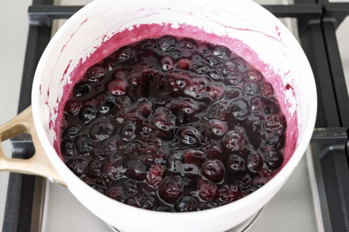 My homemade Blueberry syrup is next-level amazing! My secret ingredient? A splash of lemon! It’s the perfect balance to those sweet, juicy berries and makes your morning pancakes totally irresistible! All of the ingredients simmering in a pot.