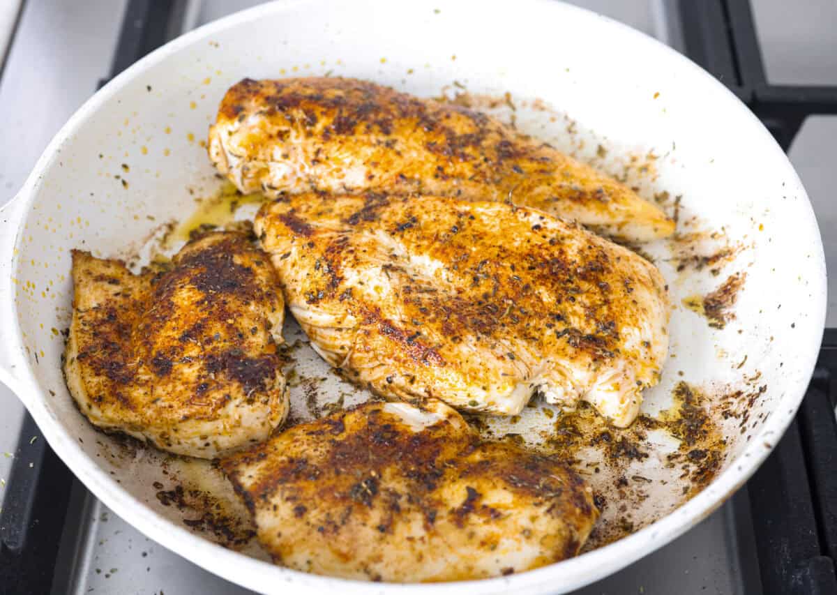 If you’re looking to save time, keep your sanity, and hit your protein goals, these chicken and rice meal prep bowls have you covered. They're flavorful, filling, and give you that “I’ve got my life together” feeling. Seasoned chicken cooking in a skillet.