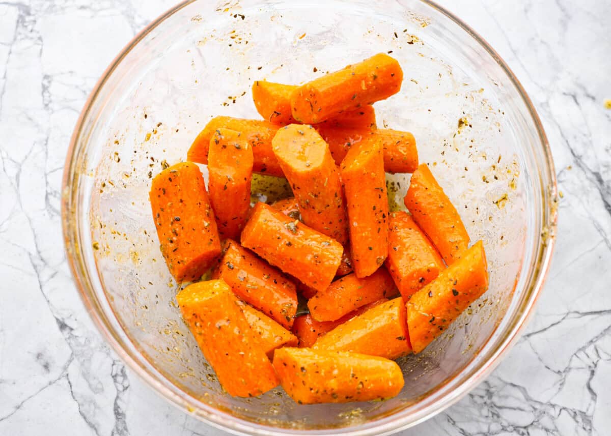 If there’s one side dish that never sticks around for long at my house, it’s these air fryer carrots! They’re crisp on the outside, tender inside, and seasoned to bring out all their natural sweetness—even the picky eaters love them! Carrots seasoned in a glass bowl.