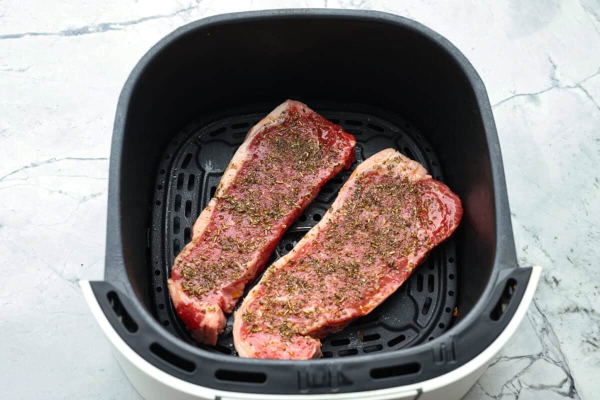My Air Fryer Steak is a favorite around here for a reason! Itโs perfectly seared, super juicy, and so full of flavorโitโs my go-to way to make steak! Steaks rubbed with seasoning placed in the air fryer basket.