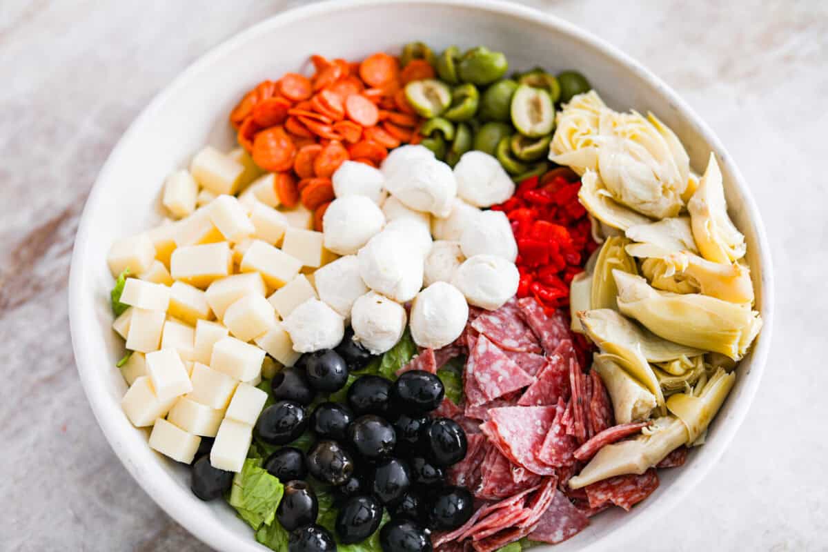 Okay, this antipasto salad? Itโs basically an Italian snack board in a bowl, and Iโmย obsessed! What makes this one a little different (and so good) is the easy lemony dressing. All of the salad ingredients in one bowl.
