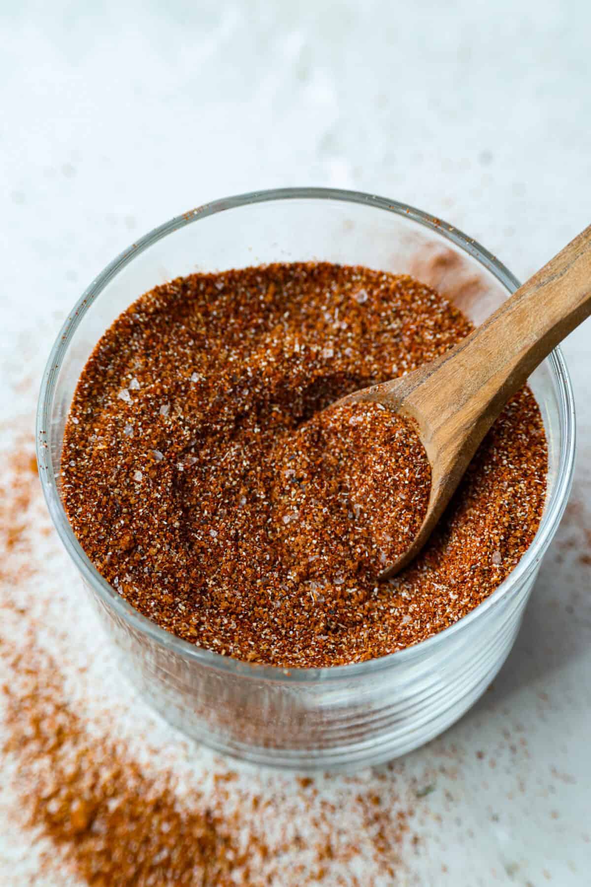 My homemade BBQ seasoning brings bold, smoky flavor to just about anything! Itโs the perfect blend of sweet, savory, and just a little kick, ready to shake onto chicken, veggies, ribs, and more. Overhead shot of a jar of homemade BBQ seasoning with a small wooden spoon.