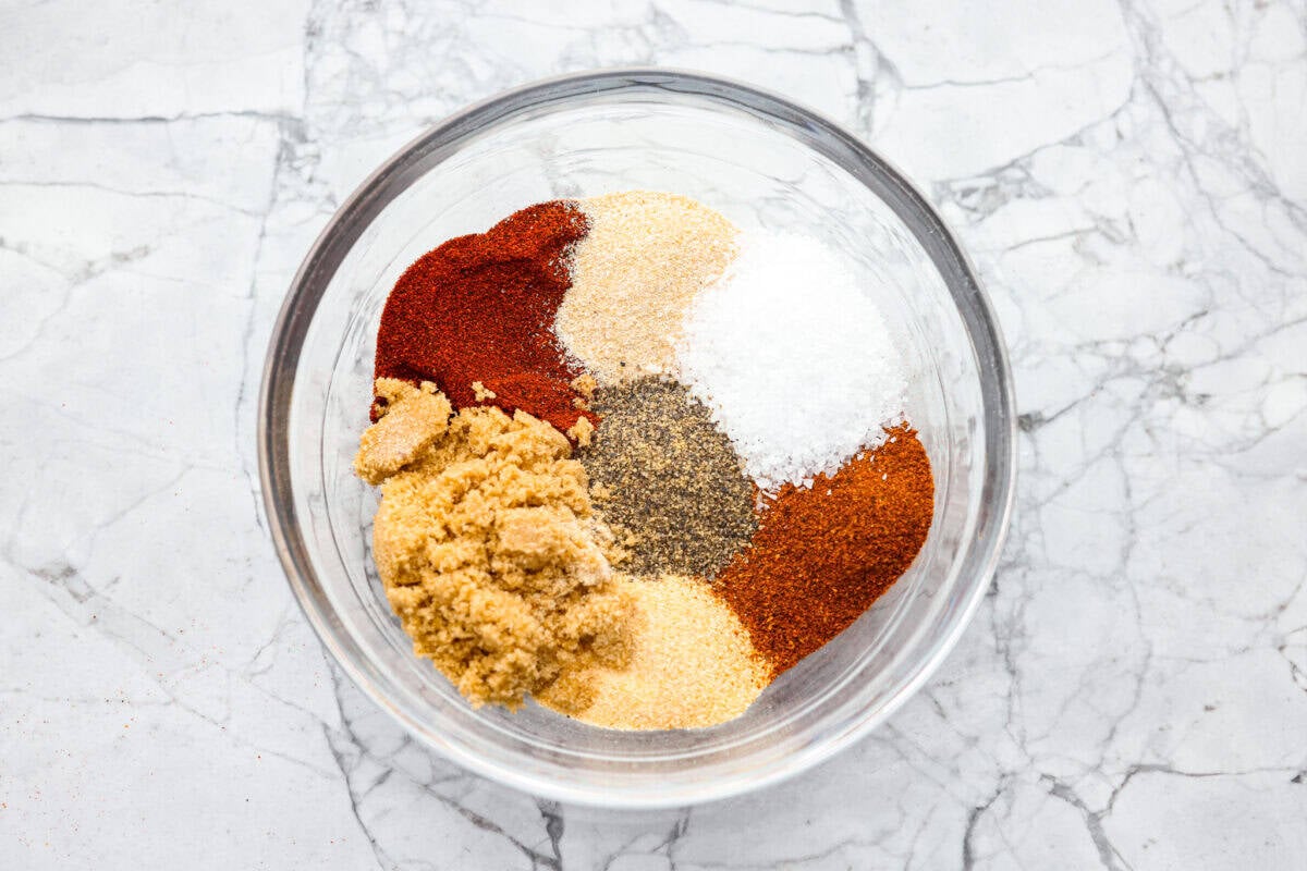 My homemade BBQ seasoning brings bold, smoky flavor to just about anything! Itโs the perfect blend of sweet, savory, and just a little kick, ready to shake onto chicken, veggies, ribs, and more. Overhead shot of all of the ingredients in piles in a bowl.