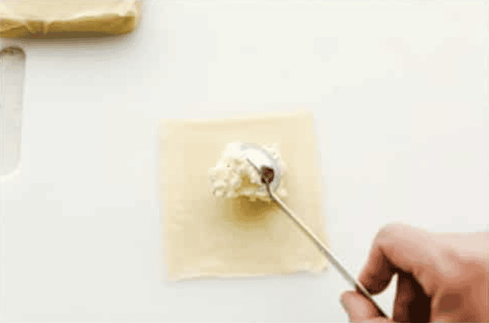 If you guys are as obsessed with cream cheese wontons as I am, you are going to love this easy-to-follow recipe! These crispy, creamy, wontons are totally doable! Cream cheese filling being placed in the middle of the wrapper.