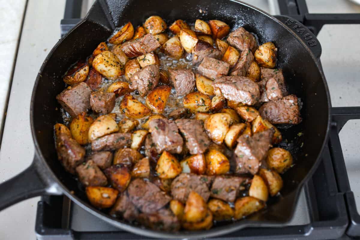 Get ready to obsess! These Garlic Butter Herb Steak Bites with Potatoes are juicy, buttery, and downright irresistible. Easy to make, crazy delicious, and pure comfort in every bite! Cooked steak and potatoes in a skillet.