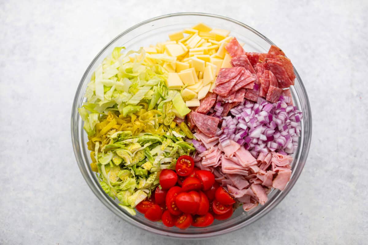 It’s like your favorite deli sub ditched the bread and got a glow-up. Think layers of crispy lettuce, your favorite meats, and a creamy dressing all in this yummy Grinder Salad form! Salad ingredients in a large bowl.