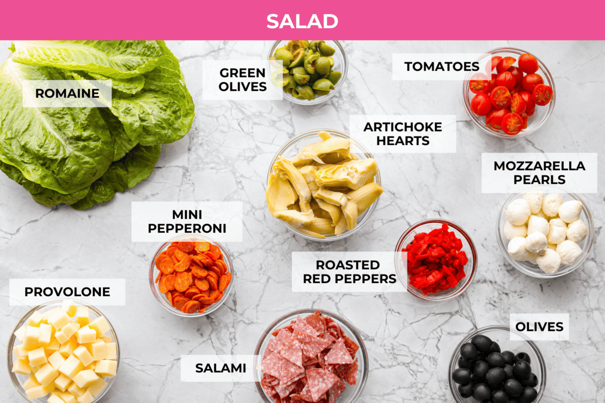 Okay, this antipasto salad? Itโs basically an Italian snack board in a bowl, and Iโmย obsessed! What makes this one a little different (and so good) is the easy lemony dressing. Overhead shot of labeled salad ingredients.