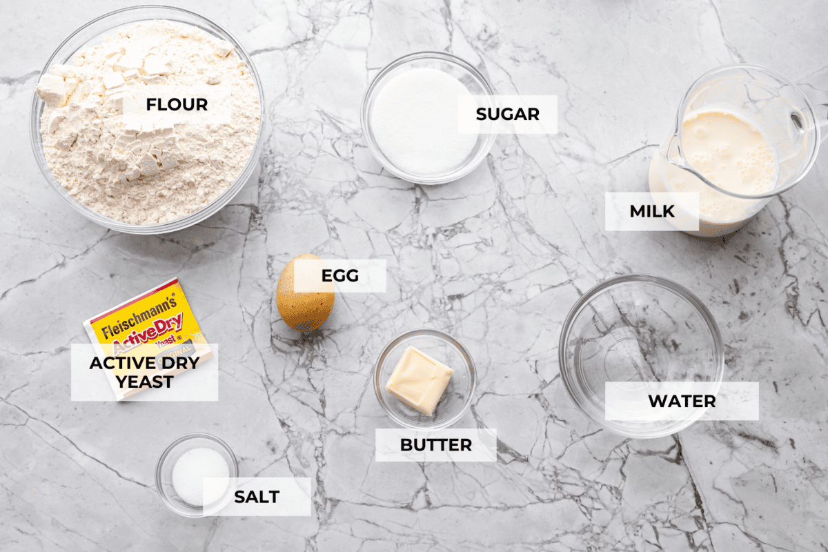 I am obsessed with Texas Roadhouse rollsโlike, zero self-control as soon as they hit the table. So, of course, I had to recreate them at home! These copycat Texas Roadhouse rolls are soft, fluffy, slightly sweet, and melt-in-your-mouth good. Overhead shot of labeled ingredients.