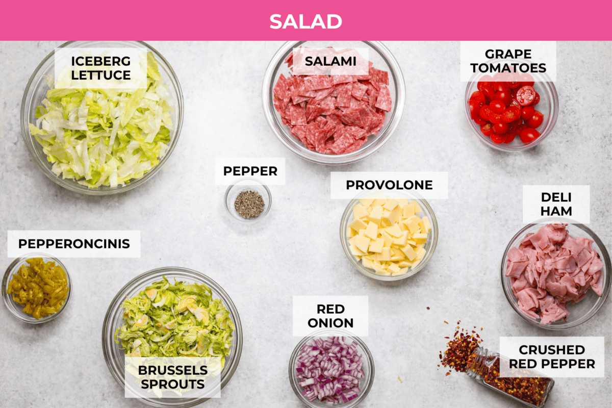 It’s like your favorite deli sub ditched the bread and got a glow-up. Think layers of crispy lettuce, your favorite meats, and a creamy dressing all in this yummy Grinder Salad form! Overhead shot of labeled salad ingredients.