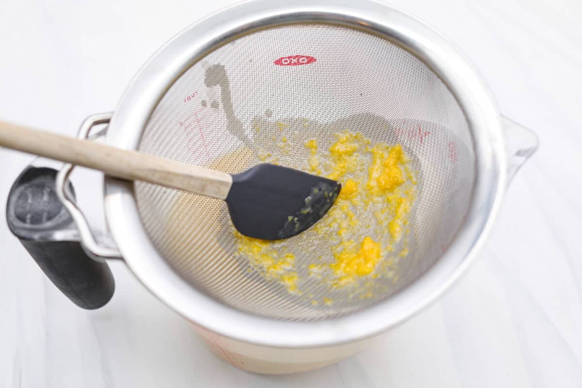 Lemon Posset- Only 5 Ingredients! Someone straining the lemon zest from the cream mixture.