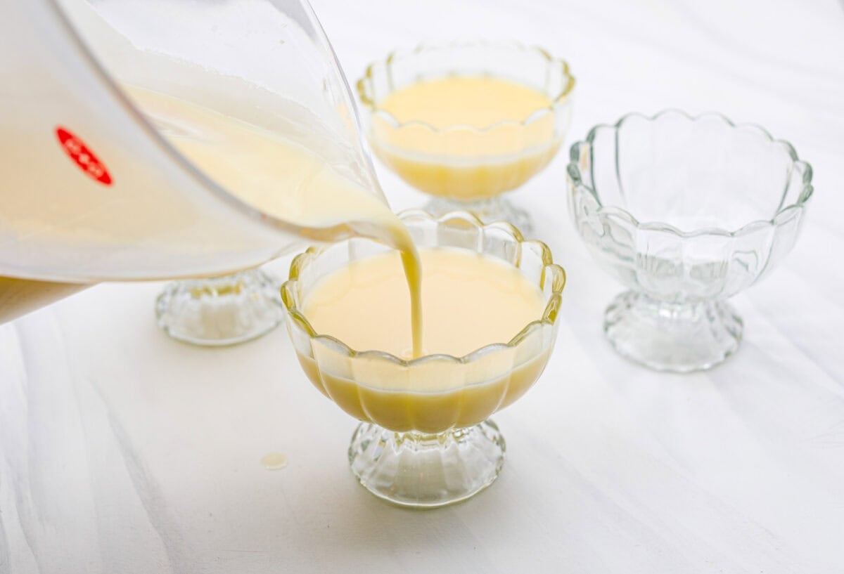 Lemon Posset- Only 5 Ingredients! Someone pouring the lemon cream into a glass serving dish.