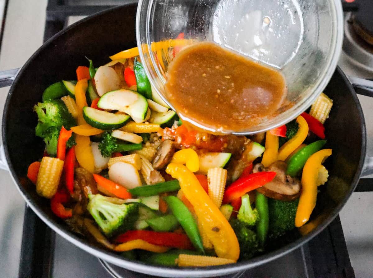 You all love this vegetable stir fry, and I donโt blame you. Itโs fast, flexible, and that sauce? So addicting! Toss in whatever veggies you have and dinnerโs done. Someone pouring the sauce over the vegetables in the wok.