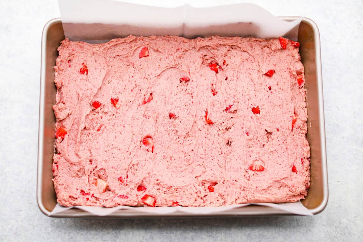 Ever since I discovered the amazing flavors that freeze-dried strawberries add, I’ve been using them as much as possible. This strawberry cake? No exception. And don’t even get me started on the frosting... It’s dangerously good. Cake batter spread out in a cake pan.