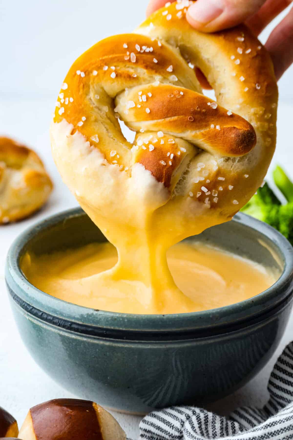Melt: In aย medium-sized saucepan, and the unsalted butter. Heat over medium heat until the butter melts. Whisk: Whisk in the all-purpose flour until it makes a roux. Stir: Add in the milk and shredded cheddar cheese to the flour mixture and stir to combine. Melt: Whisk until the cheese is melted and smooth. Someone dipping a homemade pretzel into the homemade cheese sauce.