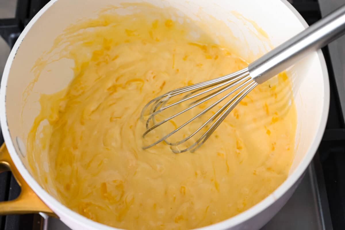 Melt: In aย medium-sized saucepan, and the unsalted butter. Heat over medium heat until the butter melts. Whisk: Whisk in the all-purpose flour until it makes a roux. Stir: Add in the milk and shredded cheddar cheese to the flour mixture and stir to combine. Melt: Whisk until the cheese is melted and smooth. Someone whisking the ingredients all together.