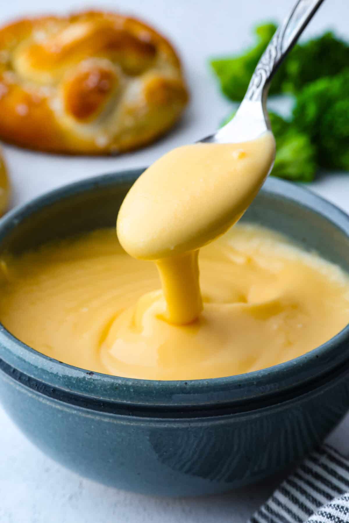 My homemade cheese sauce is ultra-creamy, wildly easy, and totally better than anything from a jar. Mild for kids, bold enough for nachosโamazing on everything! Spoon with homemade cheese sauce dripping off it into a bowl of cheese sauce.