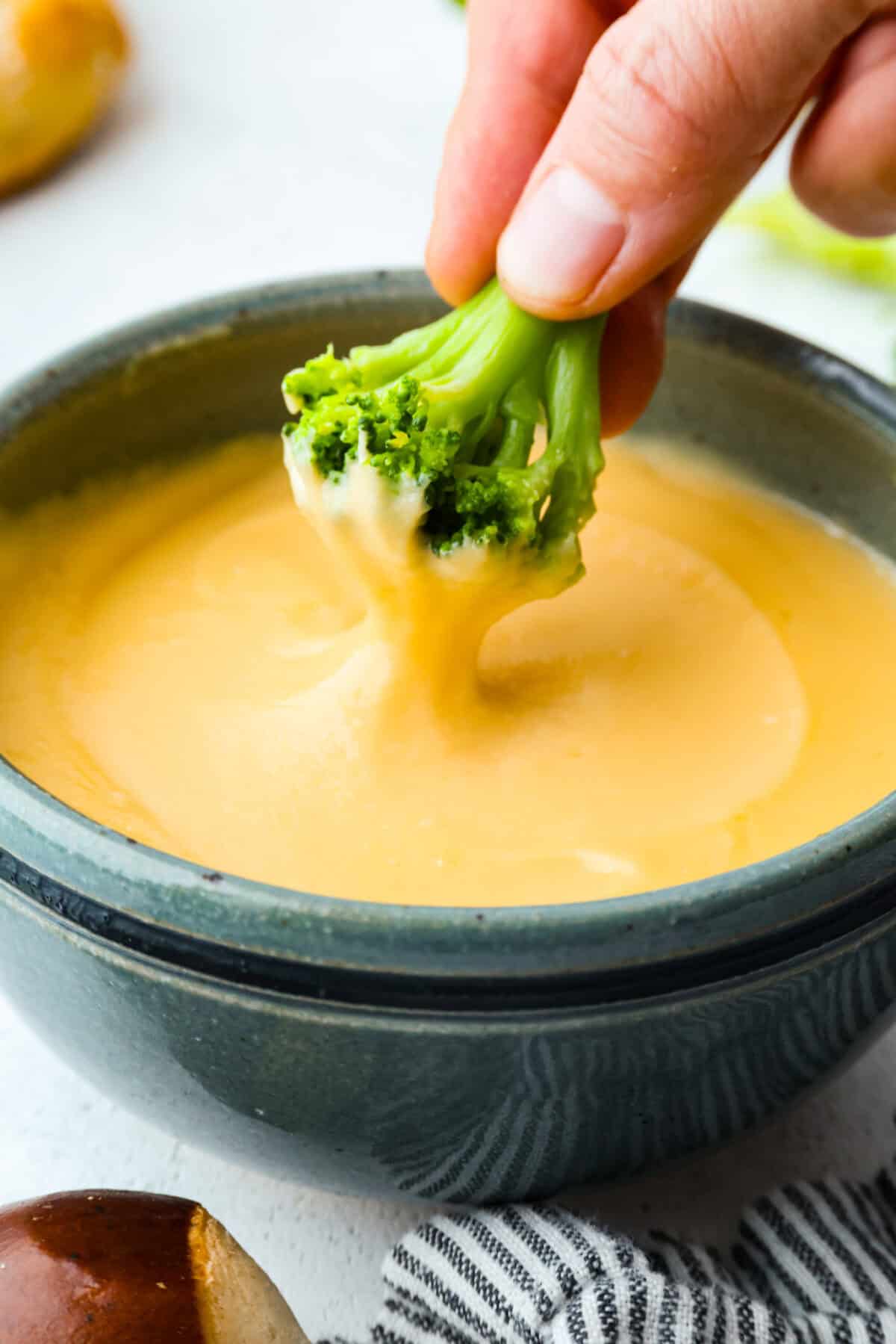 Melt: In aย medium-sized saucepan, and the unsalted butter. Heat over medium heat until the butter melts. Whisk: Whisk in the all-purpose flour until it makes a roux. Stir: Add in the milk and shredded cheddar cheese to the flour mixture and stir to combine. Melt: Whisk until the cheese is melted and smooth. Someone dipping a piece of broccoli into a bowl of homemade cheese sauce.