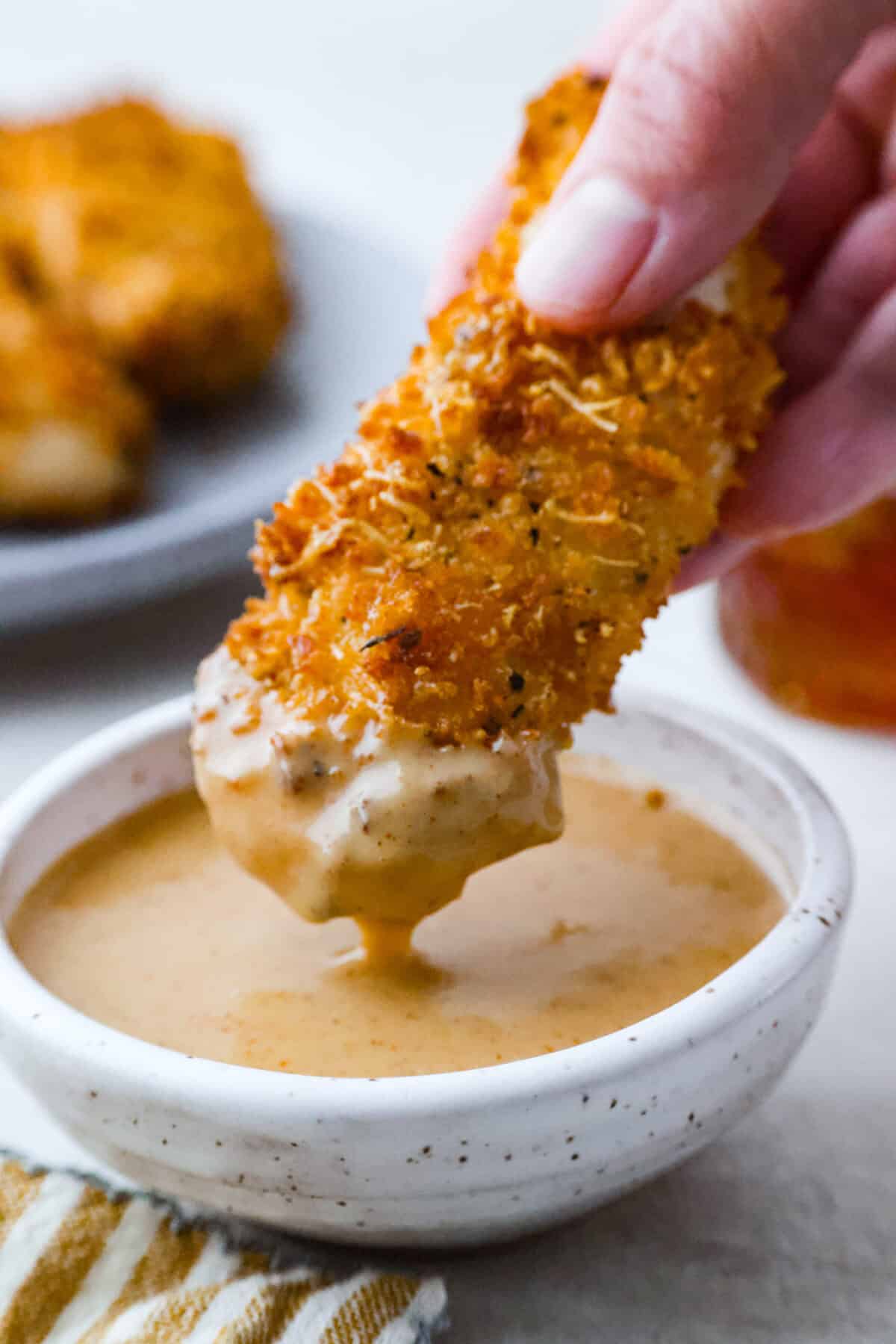 My all-time favorite sauce! This Honey Mustard is so addictive, youโll be drizzling it on everything! And the best part? It only takes 5 minutes with ingredients you probably already have in your kitchen. Someone dunking a chicken tender into honey mustard sauce.