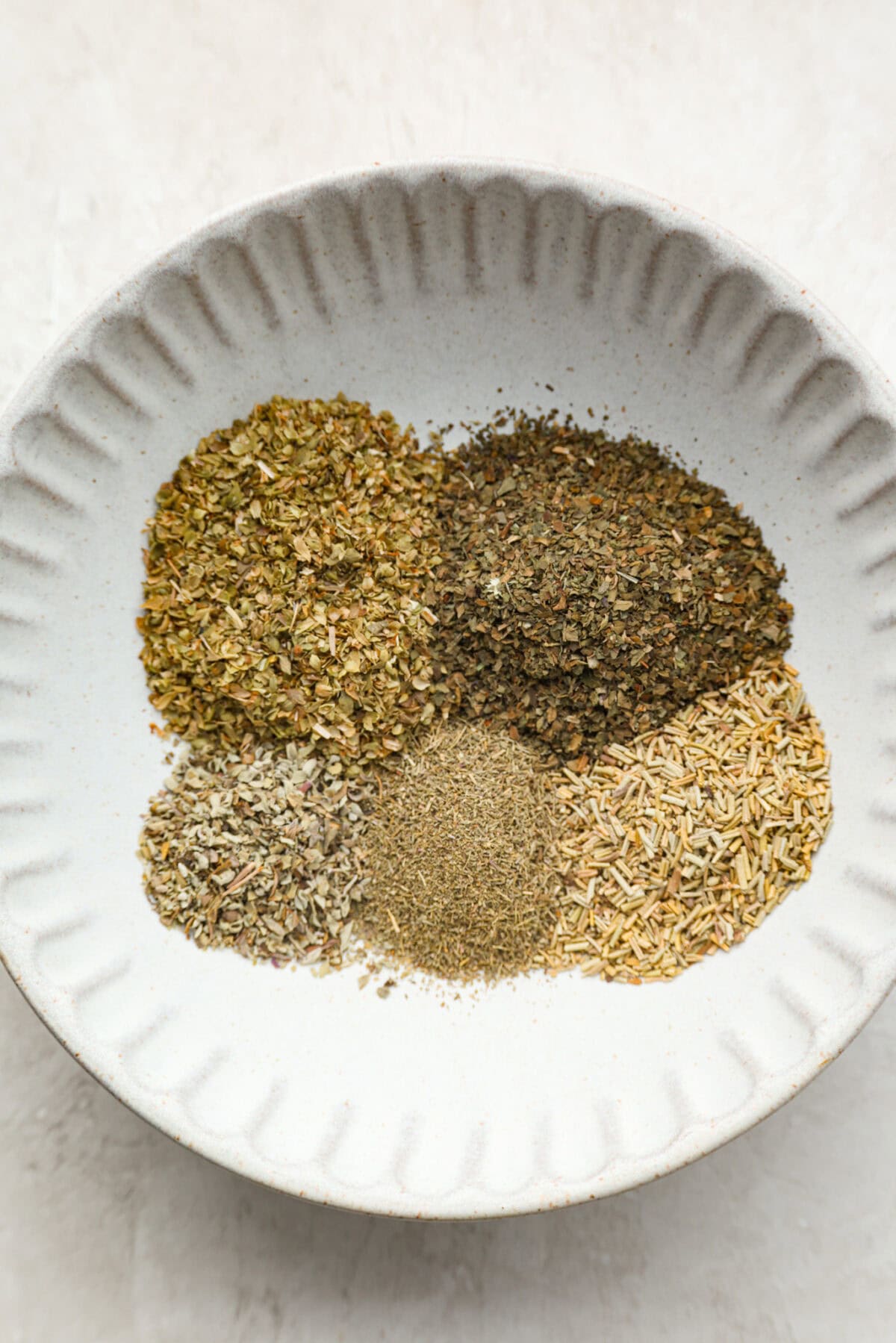 My homemade Italian seasoning is a go-to in my kitchen, and itโs quickly become a favorite with so many of you! It's bold, herby, and good enough to sprinkle on just about anything. Individual ingredients spread in piles in a bowl.
